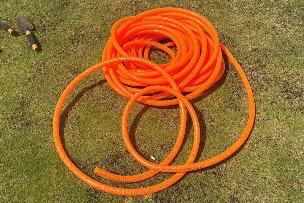 Uncoiled MIPATEX orange braided PVC garden hose placed on lawn